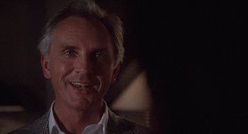 Movie still from “Wall Street” (1987), directed by Oliver Stone – A person smiling for the camera; Close Up shot, Over the shoulder angle