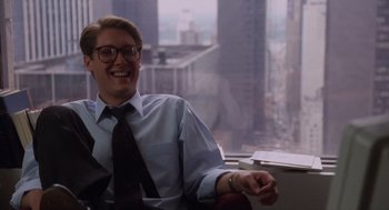 Movie still from “Wall Street” (1987), directed by Oliver Stone – A man sitting in front of a large window; Medium shot, High angle