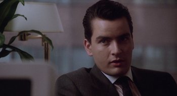 Movie still from “Wall Street” (1987), directed by Oliver Stone – A person wearing a suit and tie; Close Up shot, Over the shoulder angle