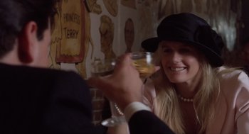Movie still from “Wall Street” (1987), directed by Oliver Stone – A woman wearing a black hat holding a glass of wine; Close Up shot, Over the shoulder angle