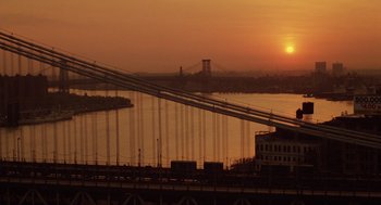 Movie still from “Wall Street” (1987), directed by Oliver Stone – The sun is setting over a river and a bridge; Extreme Wide shot, High angle