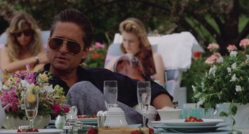 Movie still from “Wall Street” (1987), directed by Oliver Stone – A man and a woman are sitting at a table outside; Medium shot, Low angle