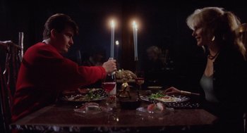 Movie still from “Wall Street” (1987), directed by Oliver Stone – A person sitting at a table with a plate of food; Medium shot, Over the shoulder angle