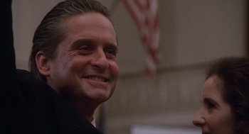 Movie still from “Wall Street” (1987), directed by Oliver Stone – A person wearing a suit and smiling; Close Up shot, Low angle