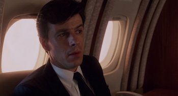 Movie still from “Wall Street” (1987), directed by Oliver Stone – A man wearing a suit and tie on a plane; Close Up shot, Low angle