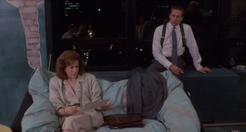 Movie still from “Wall Street” (1987), directed by Oliver Stone – A man and a woman sitting on a couch in a room; Wide shot, High angle