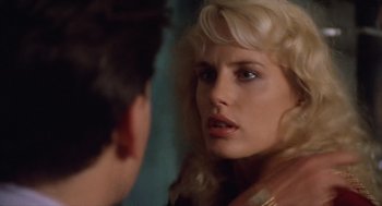 Movie still from “Wall Street” (1987), directed by Oliver Stone – A woman looking into a mirror while standing next to a man; Close Up shot, Over the shoulder angle