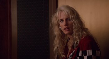 Movie still from “Wall Street” (1987), directed by Oliver Stone – A woman with long blonde curly hair wearing a red shirt; Close Up shot, Over the shoulder angle