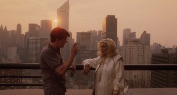 Movie still from “Wall Street” (1987), directed by Oliver Stone – A man and a woman are talking on a balcony; Wide shot, Over the shoulder angle