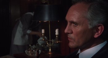 Movie still from “Wall Street” (1987), directed by Oliver Stone – A person sitting in front of a lamp; Close Up shot, Over the shoulder angle