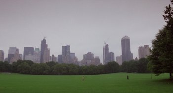 Movie still from “Wall Street” (1987), directed by Oliver Stone – A person is standing in a field near a large city; Extreme Wide shot, High angle