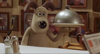 Movie still from “Wallace & Gromit: The Curse of the Were-Rabbit” (2005), directed by Nick Park – A dog holding a silver platter in front of a table; Close Up shot, Over the shoulder angle