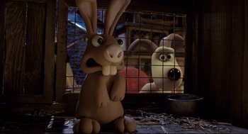 Movie still from “Wallace & Gromit: The Curse of the Were-Rabbit” (2005), directed by Nick Park – A brown rabbit sitting in front of a cage with a dog behind it; Close Up shot, Low angle