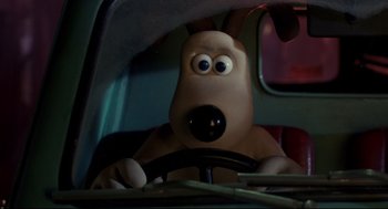 Movie still from “Wallace & Gromit: The Curse of the Were-Rabbit” (2005), directed by Nick Park – A dog driving in a car with a steering wheel; Close Up shot, High angle