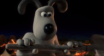 Movie still from “Wallace & Gromit: The Curse of the Were-Rabbit” (2005), directed by Nick Park – A white dog is holding a stick in front of a dark background; Close Up shot, High angle