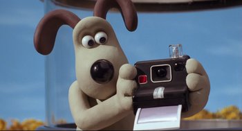 Movie still from “Wallace & Gromit: The Curse of the Were-Rabbit” (2005), directed by Nick Park – A dog holding a polaroid camera; Close Up shot, Low angle