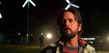 Movie still from “Another Life” (2019), created by Aaron Martin – A man with a beard is looking up at the sky; Close Up shot, Low angle