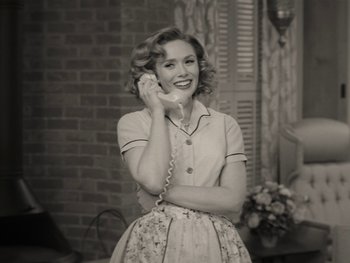 Movie still from “WandaVision” (2021), directed by Matt Shakman – A woman talking on a phone while standing in front of a brick wall; Medium shot, Low angle