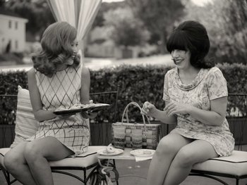 Movie still from “WandaVision” (2021), directed by Matt Shakman – Two women sitting at a table with a picnic basket; Medium shot, Low angle