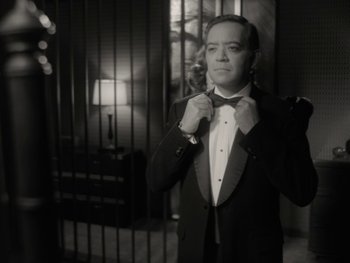 Movie still from “WandaVision” (2021), directed by Matt Shakman – A black and white photo of a man adjusting his bow tie; Medium shot, Low angle