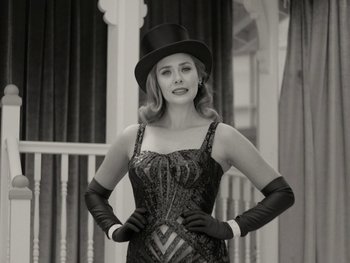 Movie still from “WandaVision” (2021), directed by Matt Shakman – A woman wearing a top hat and gloves posing for a picture; Medium shot, Low angle