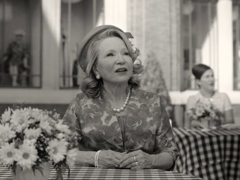 Movie still from “WandaVision” (2021), directed by Matt Shakman – An older woman sitting on a bench wearing a hat; Medium shot, Over the shoulder angle