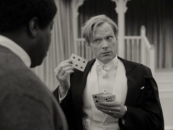 Movie still from “WandaVision” (2021), directed by Matt Shakman – A black and white photo of a man holding a deck of playing cards; Medium shot, Over the shoulder angle