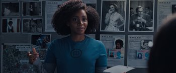 A young woman standing in front of a bunch of pictures