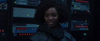 Movie still from “WandaVision” (2021), directed by Matt Shakman – A woman smiles while standing in front of a bunch of equipment; Close Up shot, Over the shoulder angle