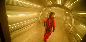 Movie still from “Another Life” (2019), created by Aaron Martin – A man in a red suit is walking in a tunnel; Wide shot, Low angle