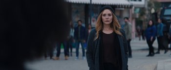 Movie still from “WandaVision” (2021), directed by Matt Shakman – A woman standing on the sidewalk in front of a crowd of onlookers; Medium shot, Over the shoulder angle