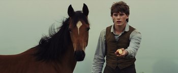 Movie still from “War Horse” (2011), directed by Steven Spielberg – A man standing next to a horse holding a piece of fruit; Close Up shot, Over the shoulder angle