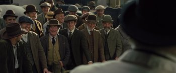 Movie still from “War Horse” (2011), directed by Steven Spielberg – A group of men in suits and hats standing next to each other; Medium shot, Low angle