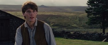 Movie still from “War Horse” (2011), directed by Steven Spielberg – A young man standing in a field near a mountain; Close Up shot, Over the shoulder angle
