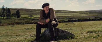 Movie still from “War Horse” (2011), directed by Steven Spielberg – A man sitting on top of a rock in a field; Medium shot, Low angle