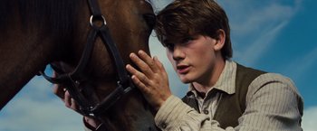 Movie still from “War Horse” (2011), directed by Steven Spielberg – A young man holding the reins of a horse; Close Up shot, Low angle