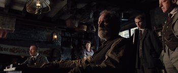 Movie still from “War Horse” (2011), directed by Steven Spielberg – An older man and a young woman are sitting in a dark room; Medium shot, Low angle