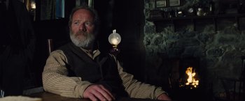 Movie still from “War Horse” (2011), directed by Steven Spielberg – An older man sitting in front of a lamp in a dark room; Medium shot, Low angle