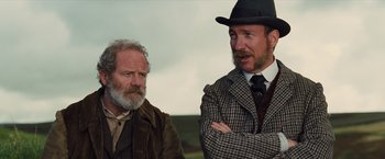 Movie still from “War Horse” (2011), directed by Steven Spielberg – Two men in suits and hats standing next to each other; Medium shot, Low angle