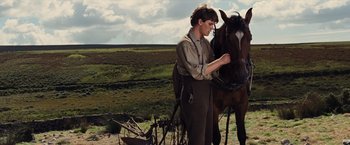 Movie still from “War Horse” (2011), directed by Steven Spielberg – A man standing next to a horse on a field; Medium shot, Low angle