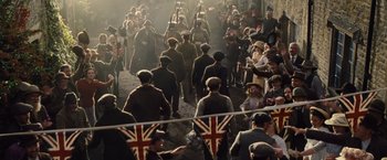 Movie still from “War Horse” (2011), directed by Steven Spielberg – A crowd of people walking down a street with british flags; Wide shot, High angle