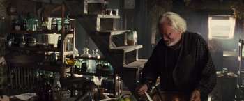 Movie still from “War Horse” (2011), directed by Steven Spielberg – An old man in a black shirt is in a room; Medium shot, High angle