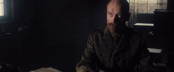 Movie still from “War Horse” (2011), directed by Steven Spielberg – A man in a military uniform sitting in a dark room; Close Up shot, Low angle