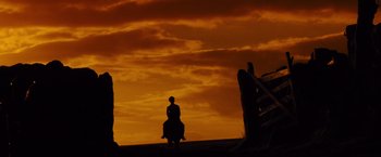Movie still from “War Horse” (2011), directed by Steven Spielberg – A person sitting on top of a horse in front of an orange sky; Extreme Wide shot, Low angle