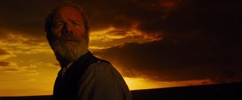 Movie still from “War Horse” (2011), directed by Steven Spielberg – An old man with a beard standing in front of a sunset; Close Up shot, Low angle