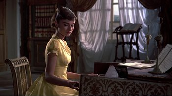 Movie still from “War and Peace” (1956), directed by King Vidor – A woman in a yellow dress using a computer; Medium shot, Low angle
