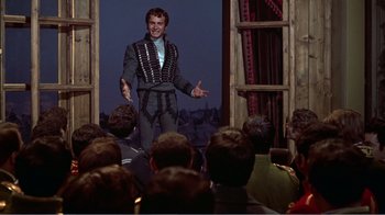 Movie still from “War and Peace” (1956), directed by King Vidor – A man is performing a show in front of an audience; Medium shot, Over the shoulder angle