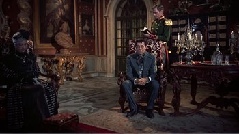 Movie still from “War and Peace” (1956), directed by King Vidor – A man sitting in a chair next to another man in a suit; Wide shot, High angle