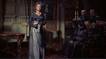 Movie still from “War and Peace” (1956), directed by King Vidor – A woman in a long dress standing in front of a group of people; Wide shot, Over the shoulder angle