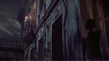 Movie still from “War and Peace” (1956), directed by King Vidor – A man standing on top of a fire escape on a building; Wide shot, Low angle